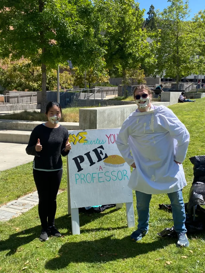 Dr. Hamachi and Andre posing in front of the AXE Pie a Professor Sign